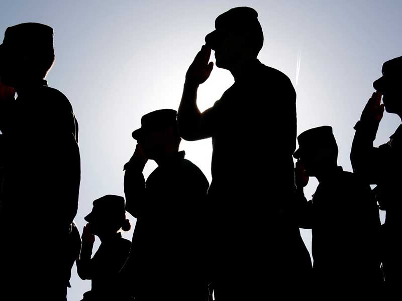 Silhouettes of military personnel saluting