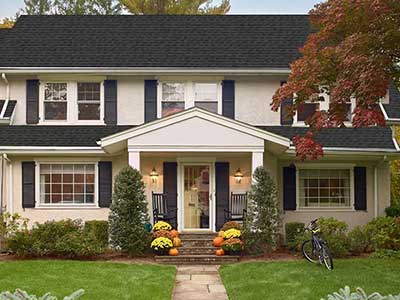 Front view of a beige mid-class, two-story home with black GAF shingles on it's roof
