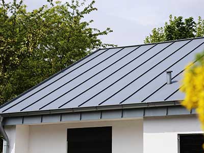 Close up of a sleek, gray metal roofing system on a small home