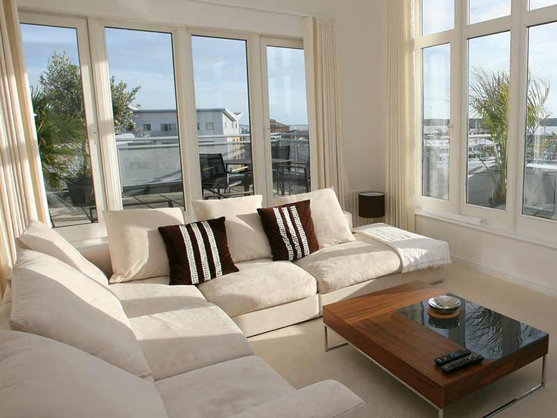 Modern white living room space with large windows on each visible wall
